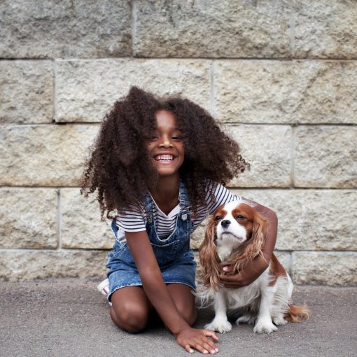 Smiling african american kid girl with dog outside. Happy child with pet