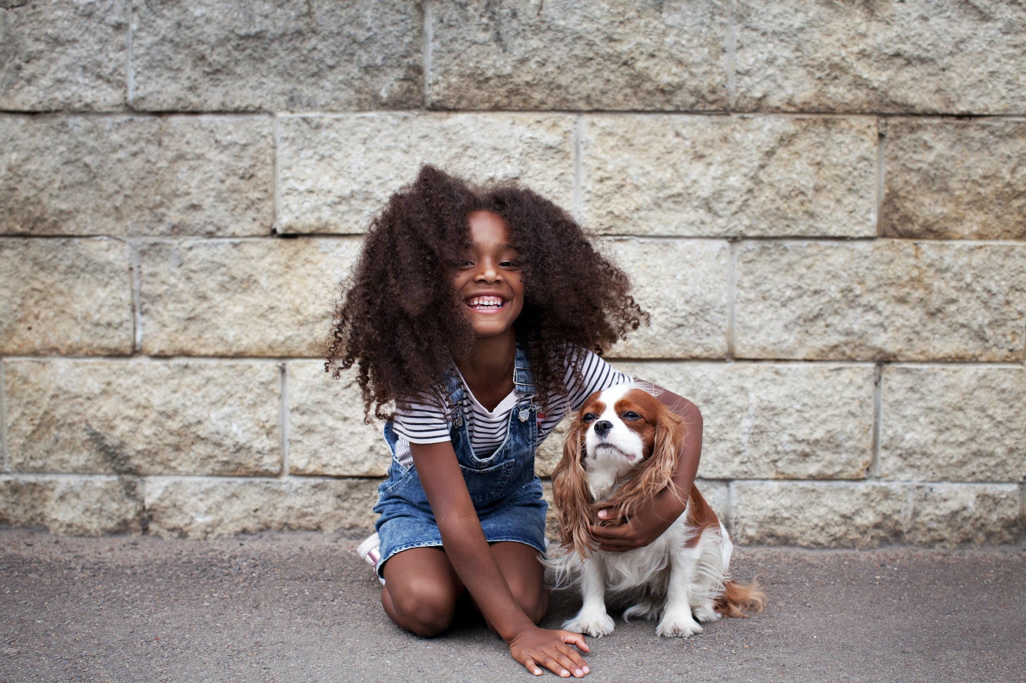 Smiling african american kid girl with dog outside. Happy child with pet